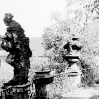 Elegant garden pathway with classical statues and stone urns.