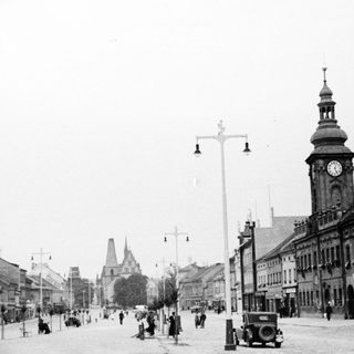 Historic town street with clock tower and early 20th-century buildings.