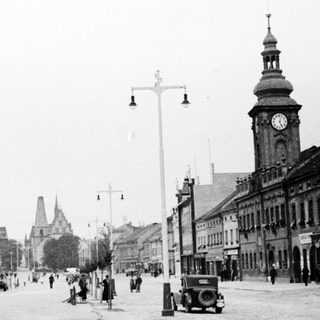 Historic town street with clock tower and early 20th-century buildings.