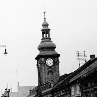 Historic town street with clock tower and early 20th-century buildings.