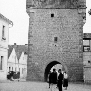 Historic stone gate tower with people in a town square.