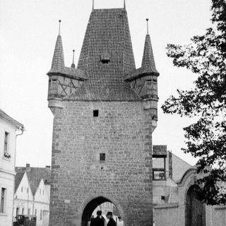 Historic stone gate tower with people in a town square.