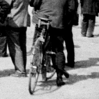 Group of men gather near a circus or fairground.