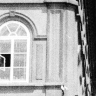 Black and white photo of a historic gate and buildings.
