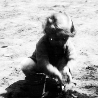 Child playing in sand with a bucket.