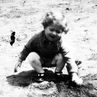 Here's a brief summary of the image: Child playing in dirt, possibly digging or squatting.