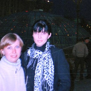 Two women stand outdoors at night, streetlights are visible.