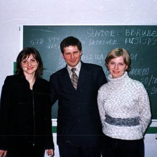 Three people pose in front of a blackboard.