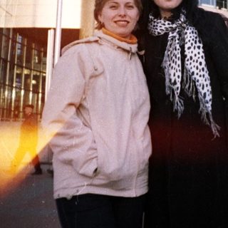 Two women stand in front of a large train station.