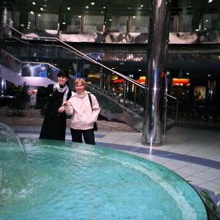 Two women stand near a fountain in a multi-level building.