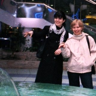 Two women stand near a fountain in a multi-level building.
