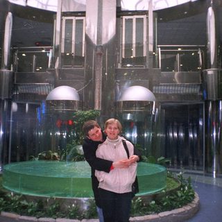 Couple poses in a modern, tiered, fountain-like interior space.