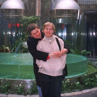 Couple poses in a modern, tiered, fountain-like interior space.