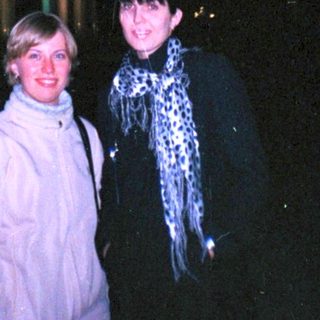 Here's a brief summary of the image: Two women stand near a lit monument at night.