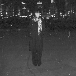Person stands in the rain amidst city lights.
