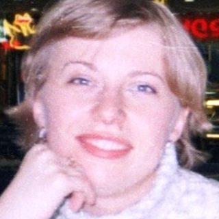 Woman sits at a table in a food court.