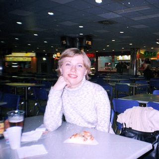 Woman sits at a table in a food court.