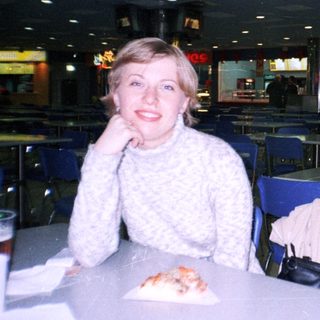 Woman sits at a table in a food court.