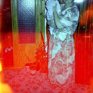 Woman holds baby in a warmly lit interior.