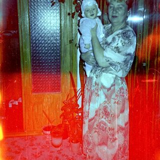 Woman holds baby in a warmly lit interior.