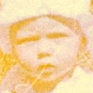 Child sits in tall grass, a vintage color photograph.