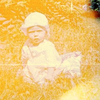 Child sits in tall grass, a vintage color photograph.