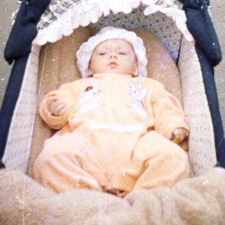 Baby sleeps in a stroller on a paved path.