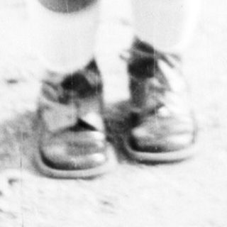 Black and white photo shows a young child standing outdoors.