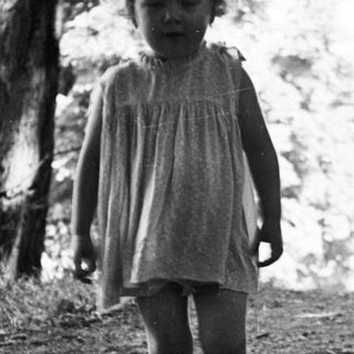Here's a brief summary of the image: Black and white photo of a young child walking on a path.