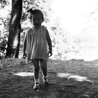 Here's a brief summary of the image: Black and white photo of a young child walking on a path.