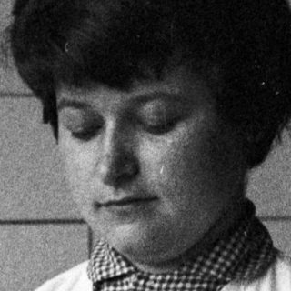 Woman in lab coat holds test tube, conducting research.