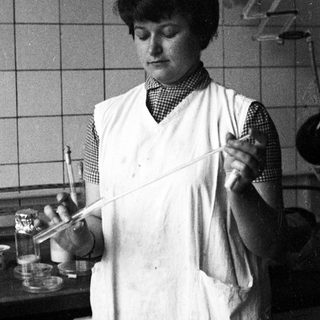 Woman in lab coat holds test tube, conducting research.