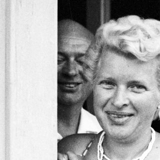 Woman in a polka dot swimsuit smiles near a doorway.