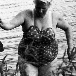 Two women wade into a body of water.