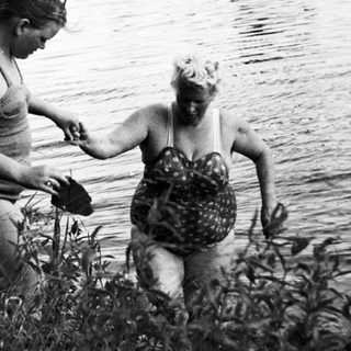 Two women wade into a body of water.