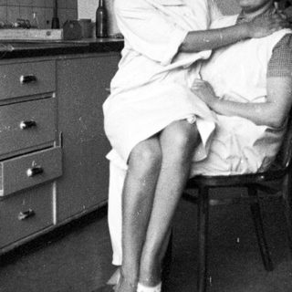 Woman in uniform examines a patient in a room.