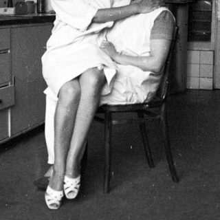 Woman in uniform examines a patient in a room.