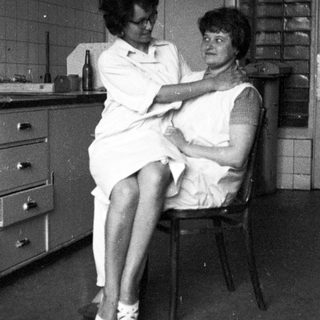 Woman in uniform examines a patient in a room.