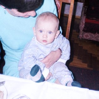 Woman sits with baby at a table, indoors.