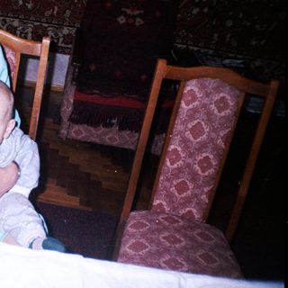 Woman sits with baby at a table, indoors.