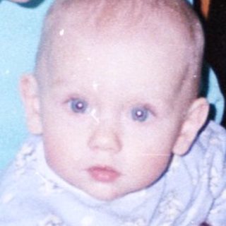Woman sits with baby at a table, indoors.