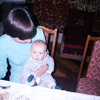 Woman sits with baby at a table, indoors.