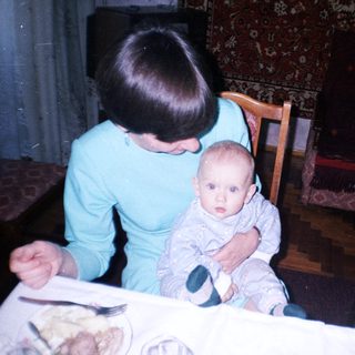 Woman sits with baby at a table, indoors.