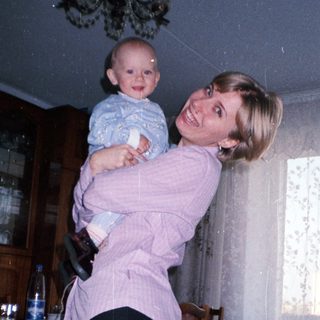 Woman holding baby in a dining room setting.