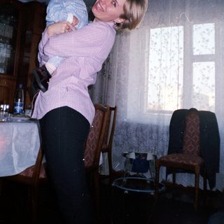 Woman holding baby in a dining room setting.