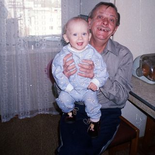 Man holds baby in kitchen, smiling for a photo.