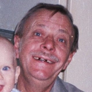 Man holds baby in kitchen, smiling for a photo.