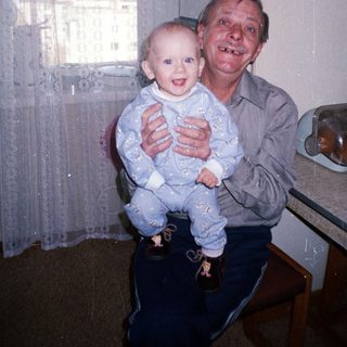 Man holds baby in kitchen, smiling for a photo.