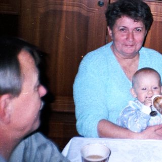Woman holding baby at a table with family.