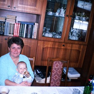 Woman holding baby at a table with family.